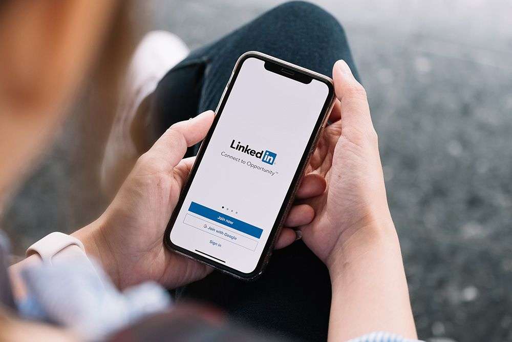 A person building better business relationships by logging into Linkedin on their phone.