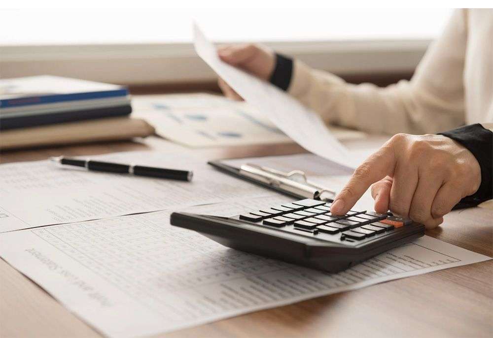 A closeup of a person using a calculator and going through finances.